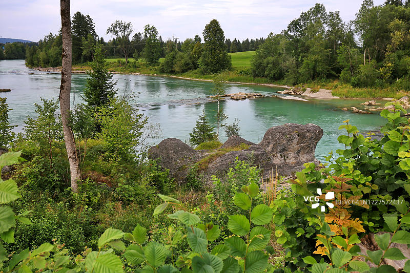 莱希河畔莱希布鲁克的河岸风光，远处可见岩层，背景是树木繁茂的区域和蓝天白云，宁静祥和，德国巴伐利亚图片素材