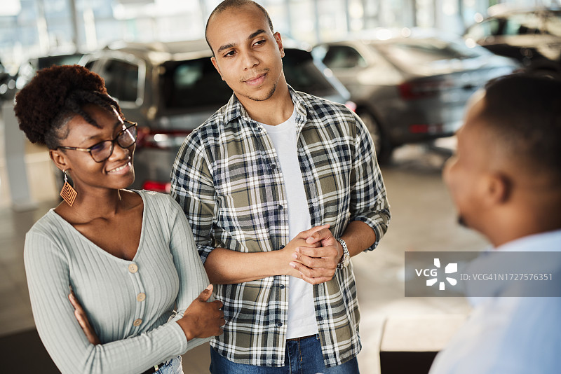 在展厅与汽车销售交谈的非洲裔情侣图片素材