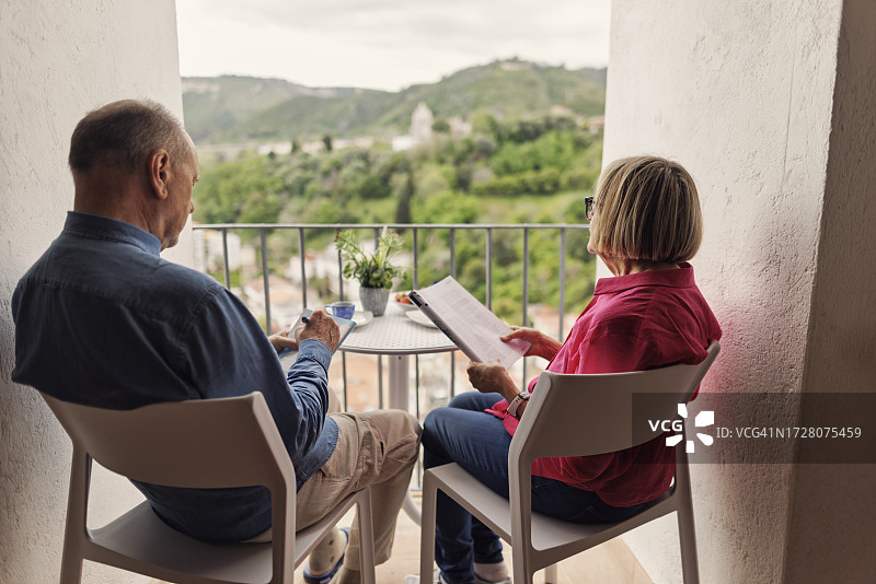 年长夫妇在阳台上放松身心，啜饮咖啡图片素材