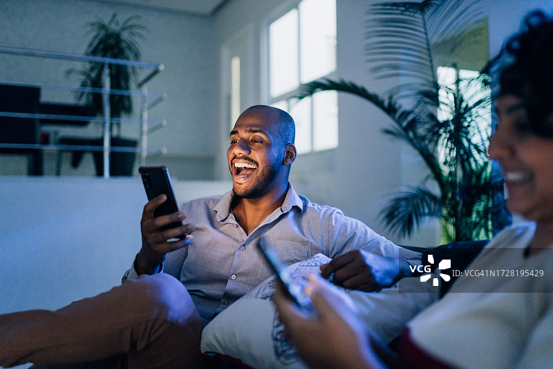 男人晚上用智能手机观看比赛图片素材