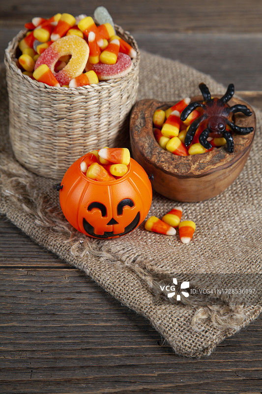 万圣节糖果玉米和南瓜灯碗在木制乡村桌子上图片素材