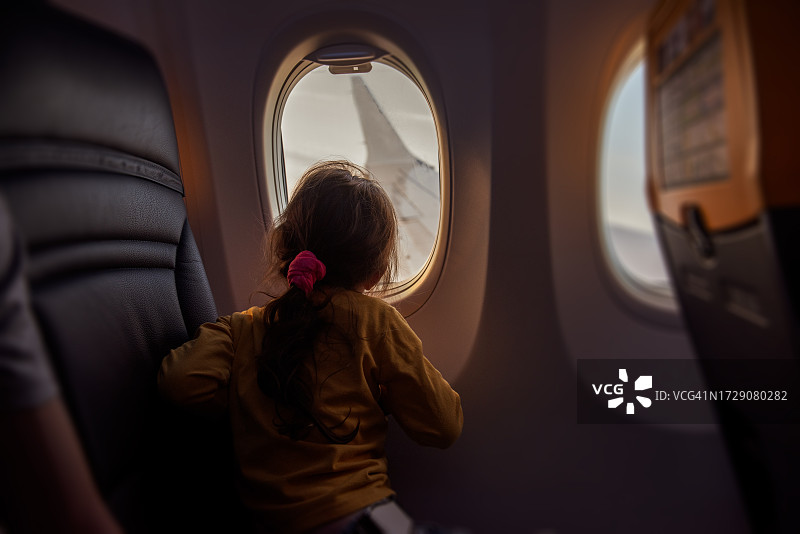 小女孩在飞机上看着舷窗外的机翼，不害怕飞行图片素材