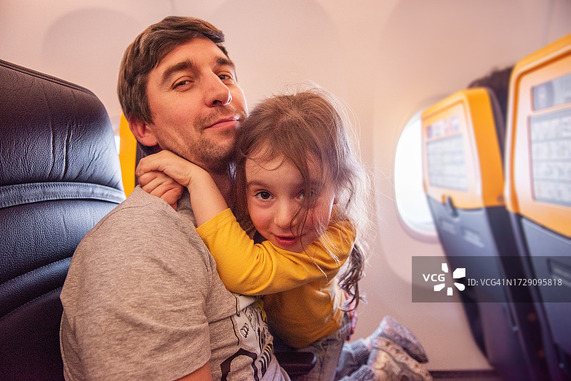 父女在飞机舷窗旁拥抱玩耍图片素材