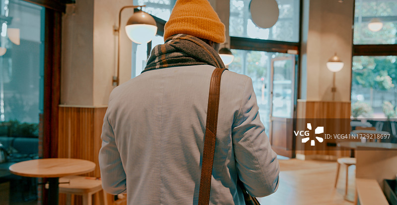 背影，时尚，一个人在早晨的咖啡店喝饮料，远程工作或通勤。步行，冬天，一个男人在餐馆或咖啡馆喝一杯热饮或早餐或午餐图片素材