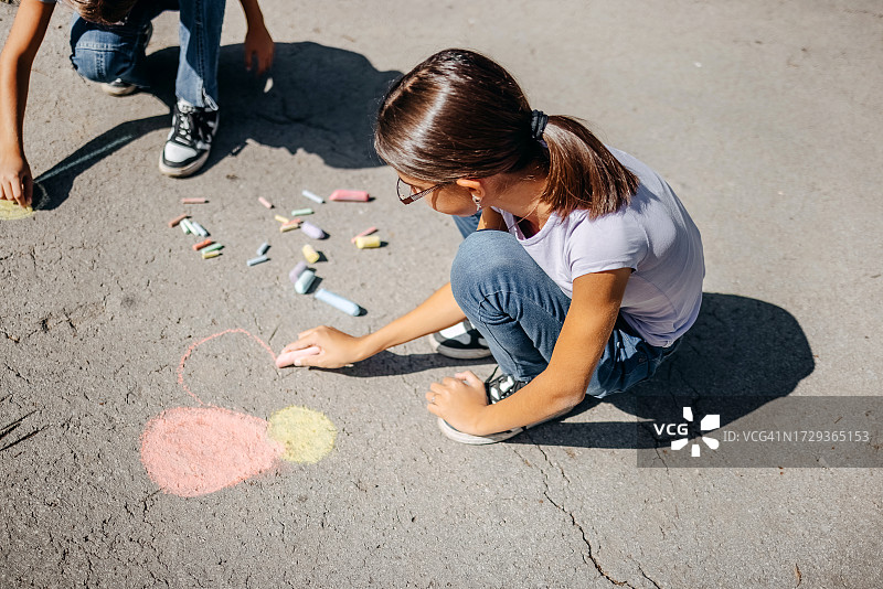 女孩们在公园里用粉笔画画，玩得很开心图片素材