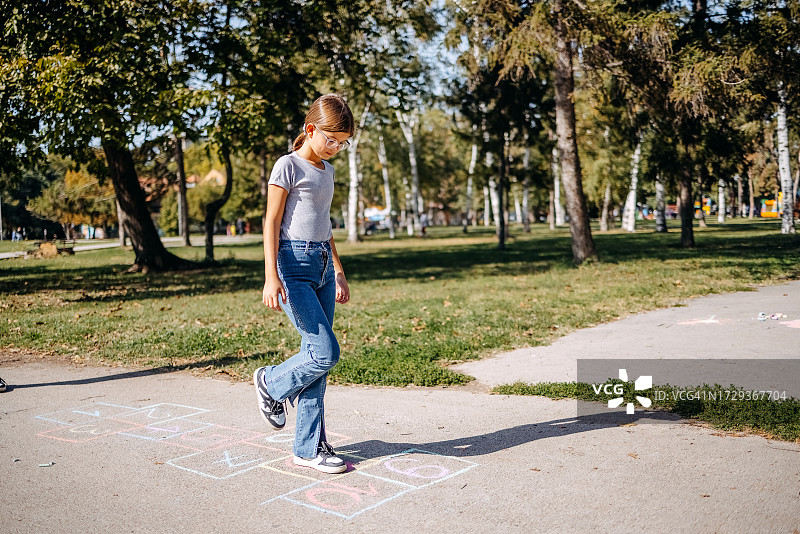 女孩们在公园里用粉笔画画和玩跳房子图片素材