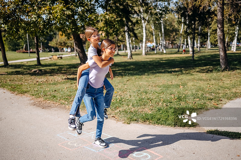 女孩们在公园里用粉笔画画和玩跳房子图片素材