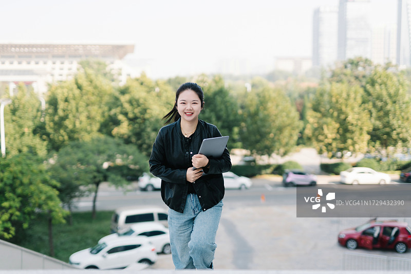 中国女大学生在校园里拿着笔记本电脑图片素材