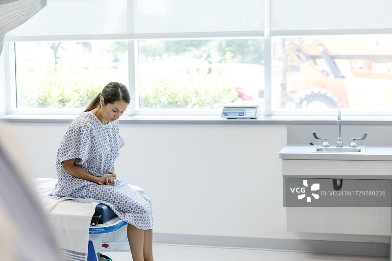 坐在病床上，痛苦的女人等待医生图片素材