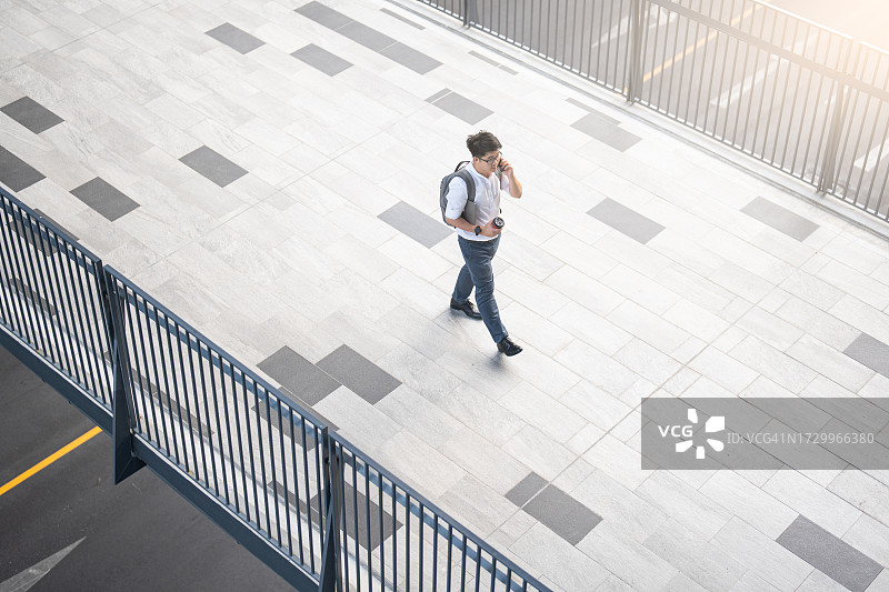 自信的亚洲男商人，拿着包走在楼前图片素材