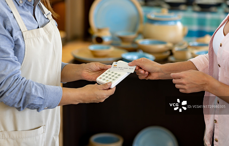 女人在陶器店进行非接触式支付图片素材