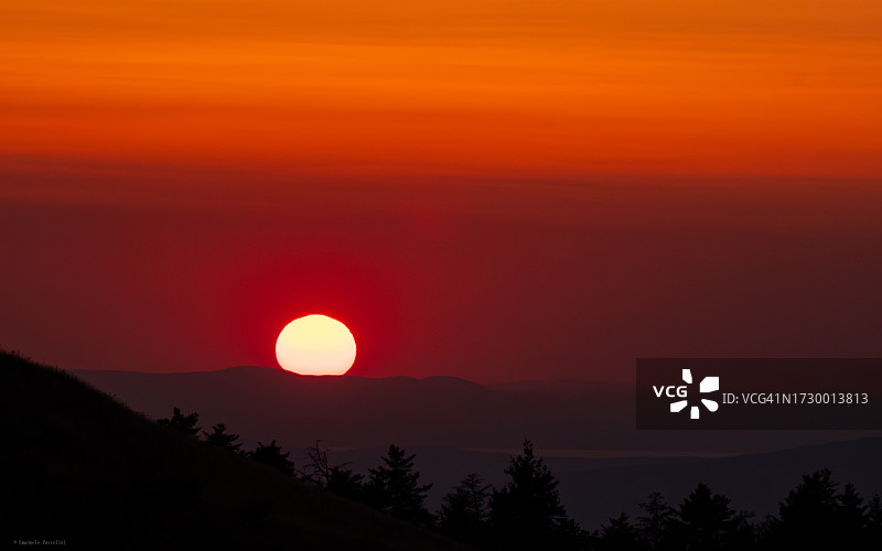 橙色天空映衬下群山剪影的美景图片素材
