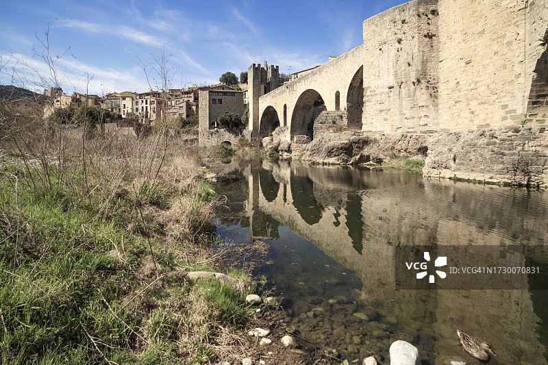 低角度拍摄的罗马式桥梁（埃尔蓬特维尔桥）在西班牙赫罗纳贝萨卢的倒影图片素材