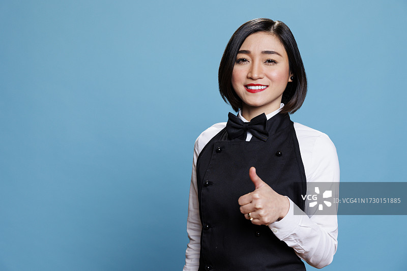 在蓝色背景下手势的微笑年轻女子肖像图片素材