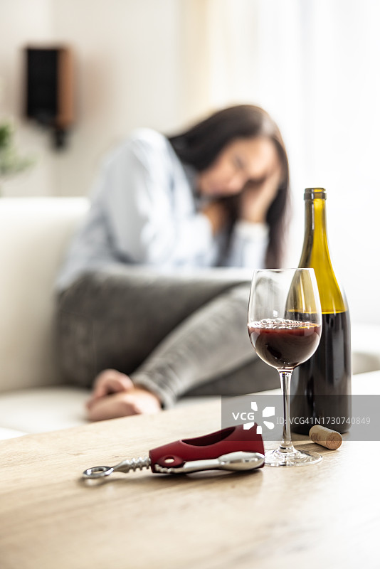 不开心的女人拿着酒瓶坐在沙发上图片素材