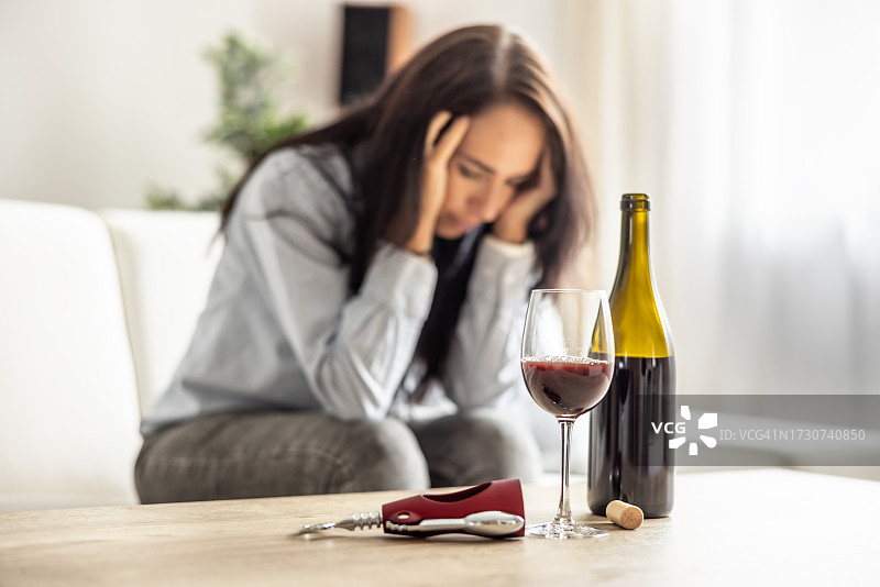 不开心的女人拿着酒瓶坐在沙发上图片素材