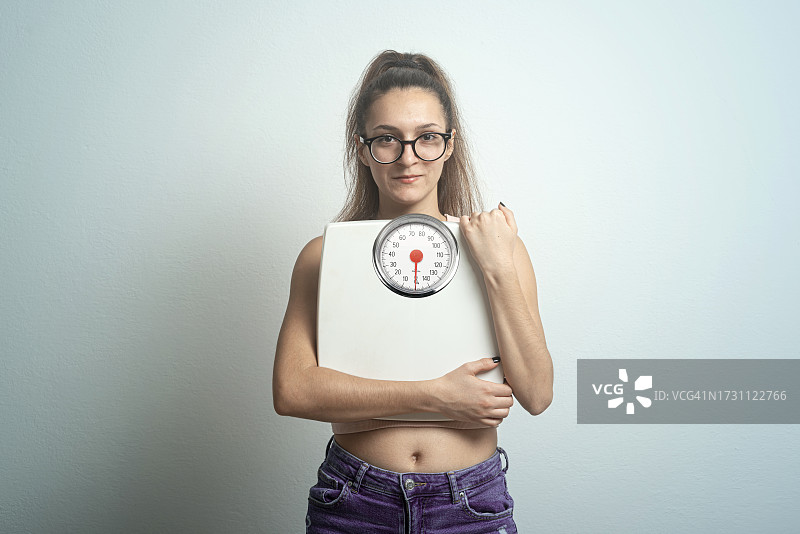 拥抱浴室秤的年轻女人图片素材