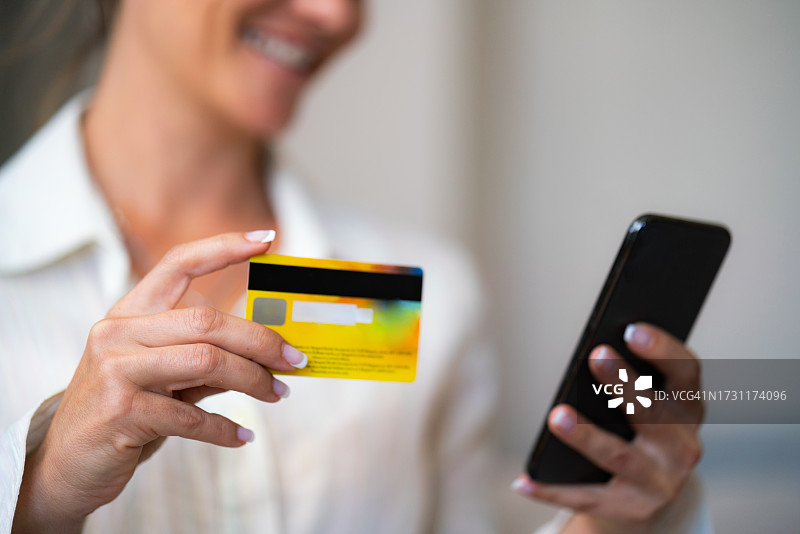 女人在家用信用卡和智能手机在线购物图片素材