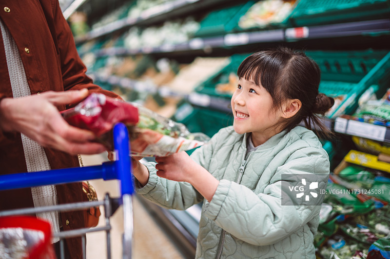 快乐的女孩和妈妈在超市购买食物图片素材