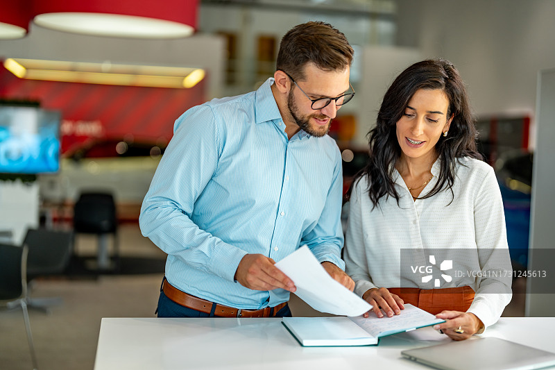 在现代办公室一起阅读文件的两位商人图片素材