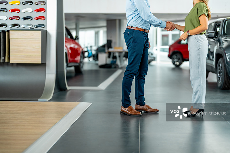 汽车销售员在汽车展厅与顾客达成交易图片素材