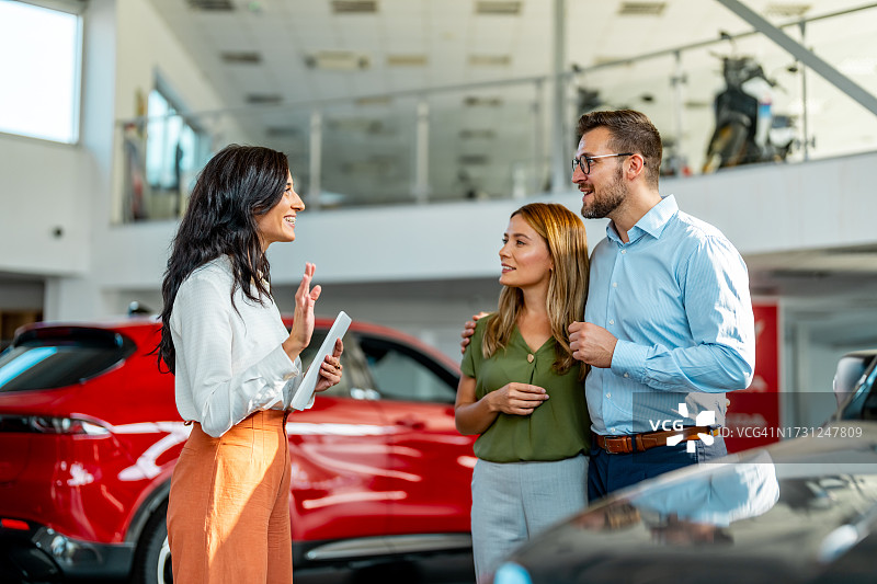女售货员在汽车经销店向顾客展示新款电动汽车图片素材