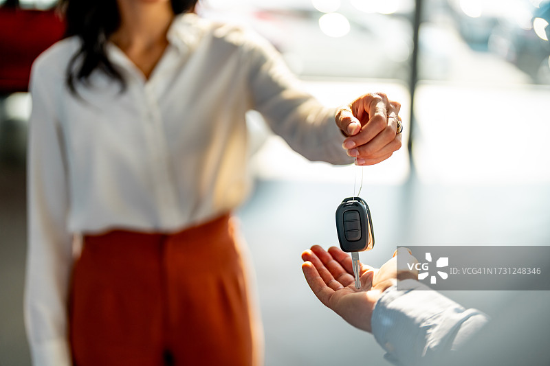 销售人员在汽车经销店将车钥匙交给顾客图片素材