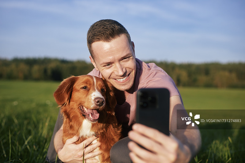 男人在草地上和狗自拍图片素材