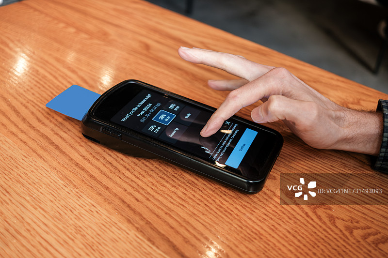 男子在餐厅用信用卡在无线设备上支付账单图片素材
