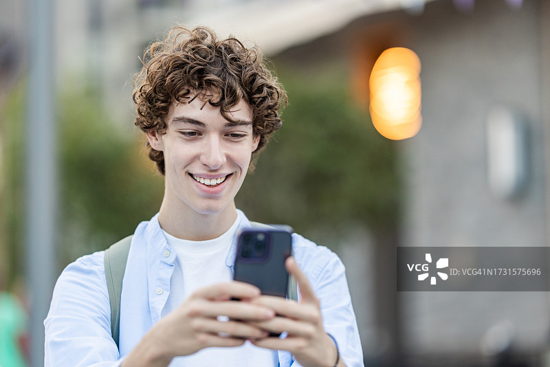 在户外享受阳光明媚的一天，使用手机的年轻男人的肖像图片素材