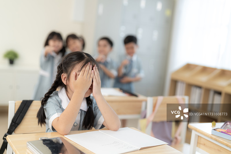 教室里表达悲伤和哭泣的亚洲学龄前儿童图片素材