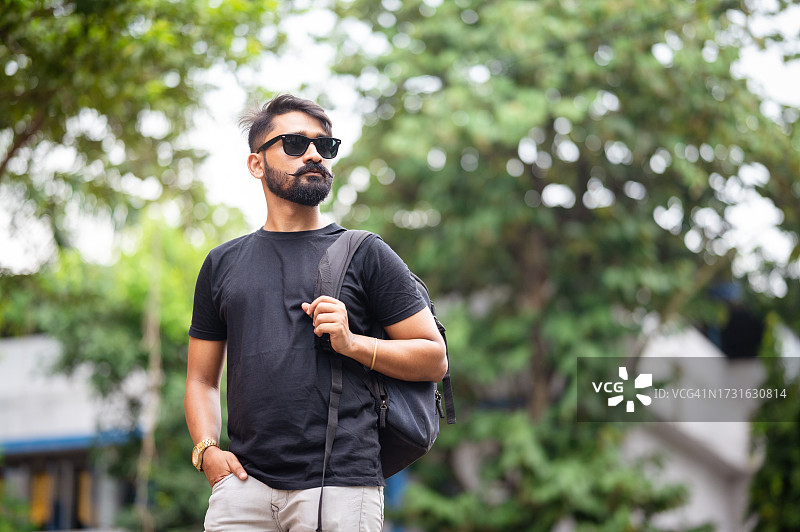 背着背包在城市中行走的年轻帅气男子图片素材