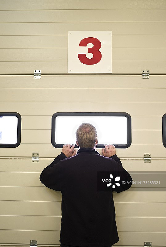 男人从车库门的窗户往外看图片素材