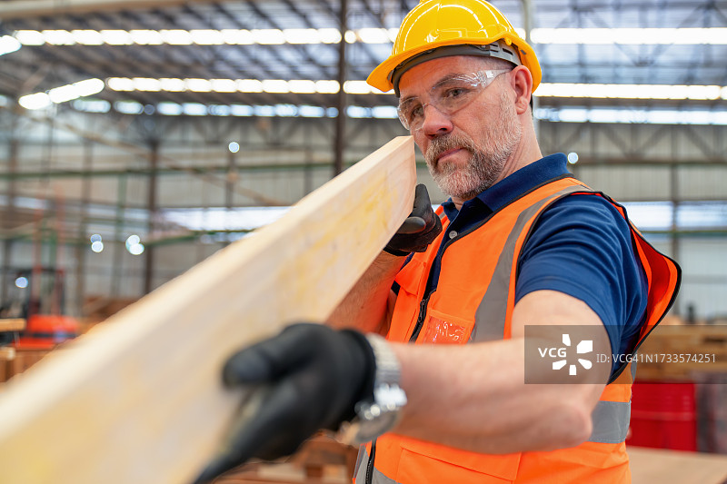 成人检查木材的笔直度，然后运送到托盘制造厂进行托盘化处理。质量控制保证。图片素材