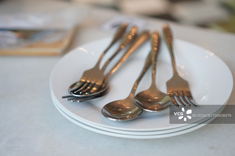 放在白色盘子上的不锈钢勺子和叉子图片素材