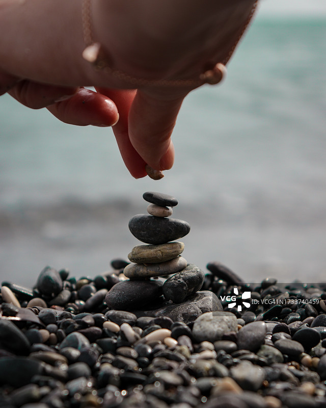 手部特写在沙滩上堆叠鹅卵石图片素材
