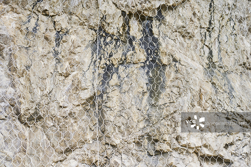前景中一些沙岩的纹理正面图，上面覆盖着网，没有人。图片素材