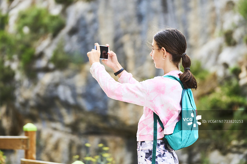 年轻女子徒步旅行，用手机拍照图片素材