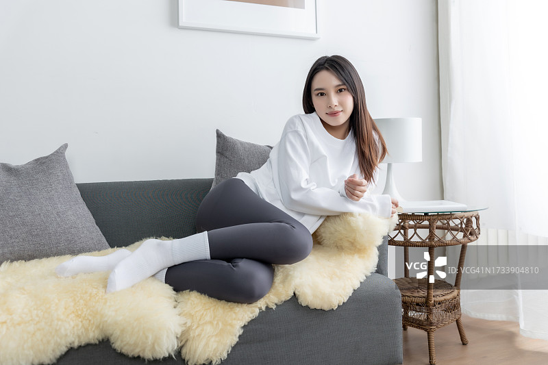 年轻漂亮的亚洲女孩坐在客厅舒适的沙发上休息图片素材