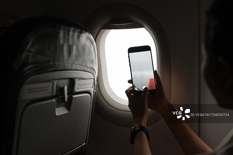亚裔女性在飞机内用智能手机拍照图片素材