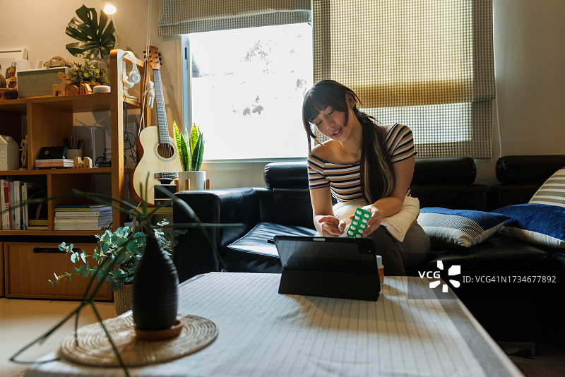 亚洲女性在家中客厅与医生进行视频在线咨询图片素材