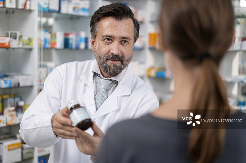 男药剂师在药房向老年患者提供处方药图片素材