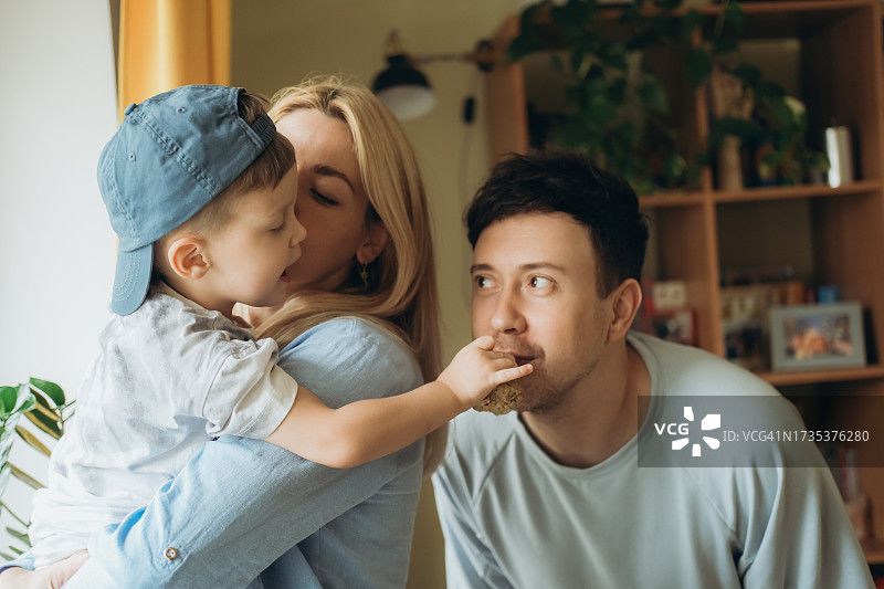 男孩坐在母亲的怀里喂父亲图片素材