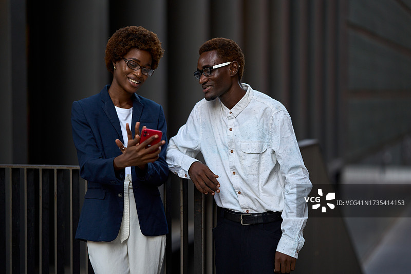 在商业大楼外使用手机的非洲同事图片素材