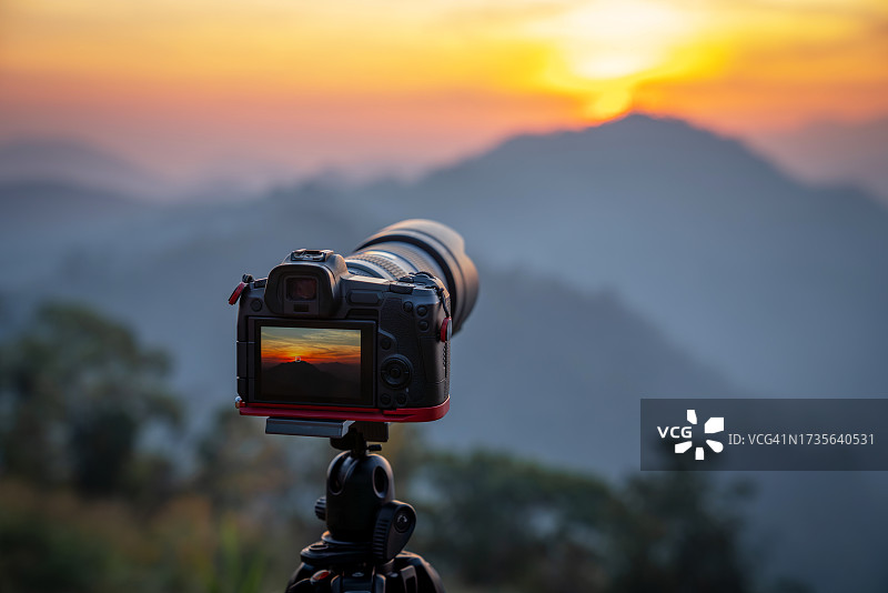 在日出时拍摄风景照片的相机特写。周末快乐旅行。图片素材