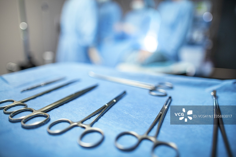 手术室托盘上的外科设备，背景中有医护人员图片素材