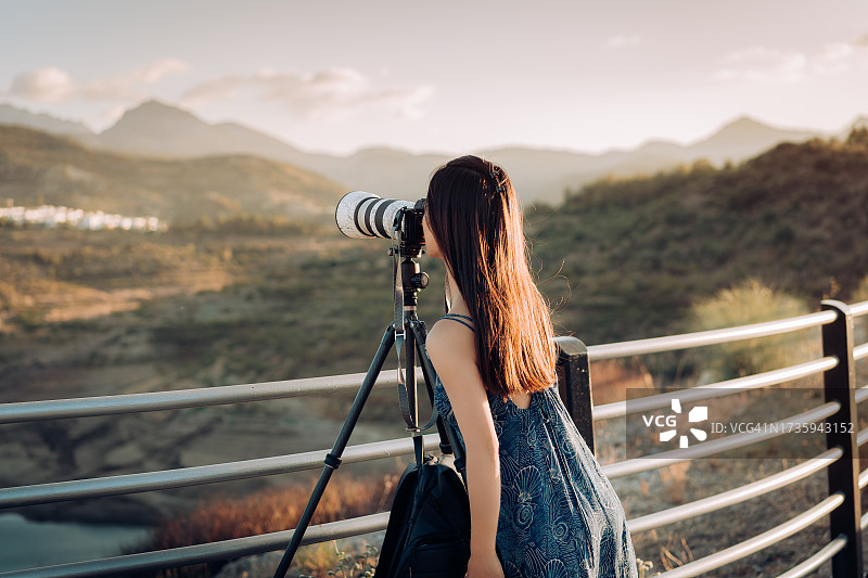 日落时分用数码相机拍照的女摄影师图片素材