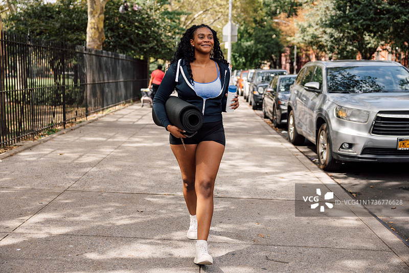 携带瑜伽垫去参加运动训练课程的女人图片素材