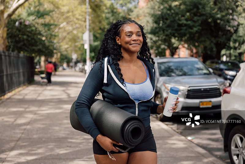 携带瑜伽垫去参加运动训练课程的女人图片素材