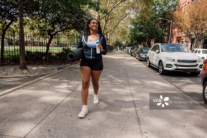 携带瑜伽垫去参加运动训练课程的女人图片素材